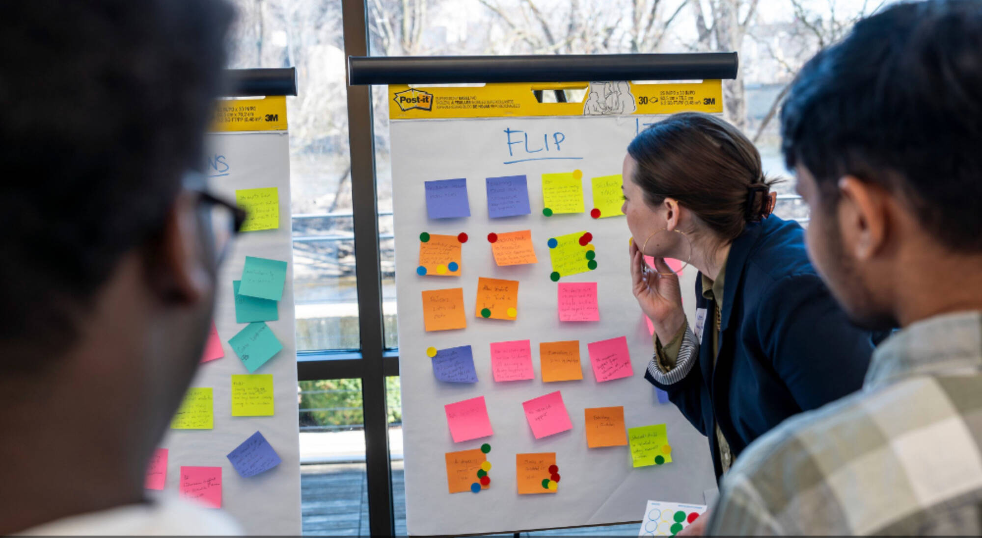 Woman looking at whiteboard with sticky notes of ideas on it.